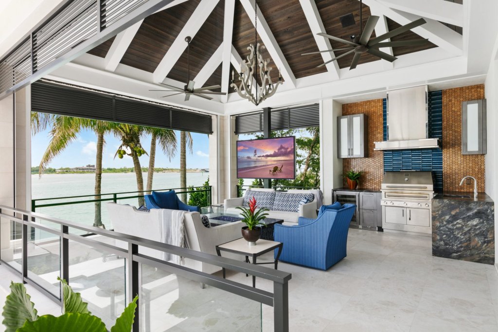 Terraza de casa inteligente frente al mar con TV exterior, ventiladores y cocina, sistema con protección eléctrica